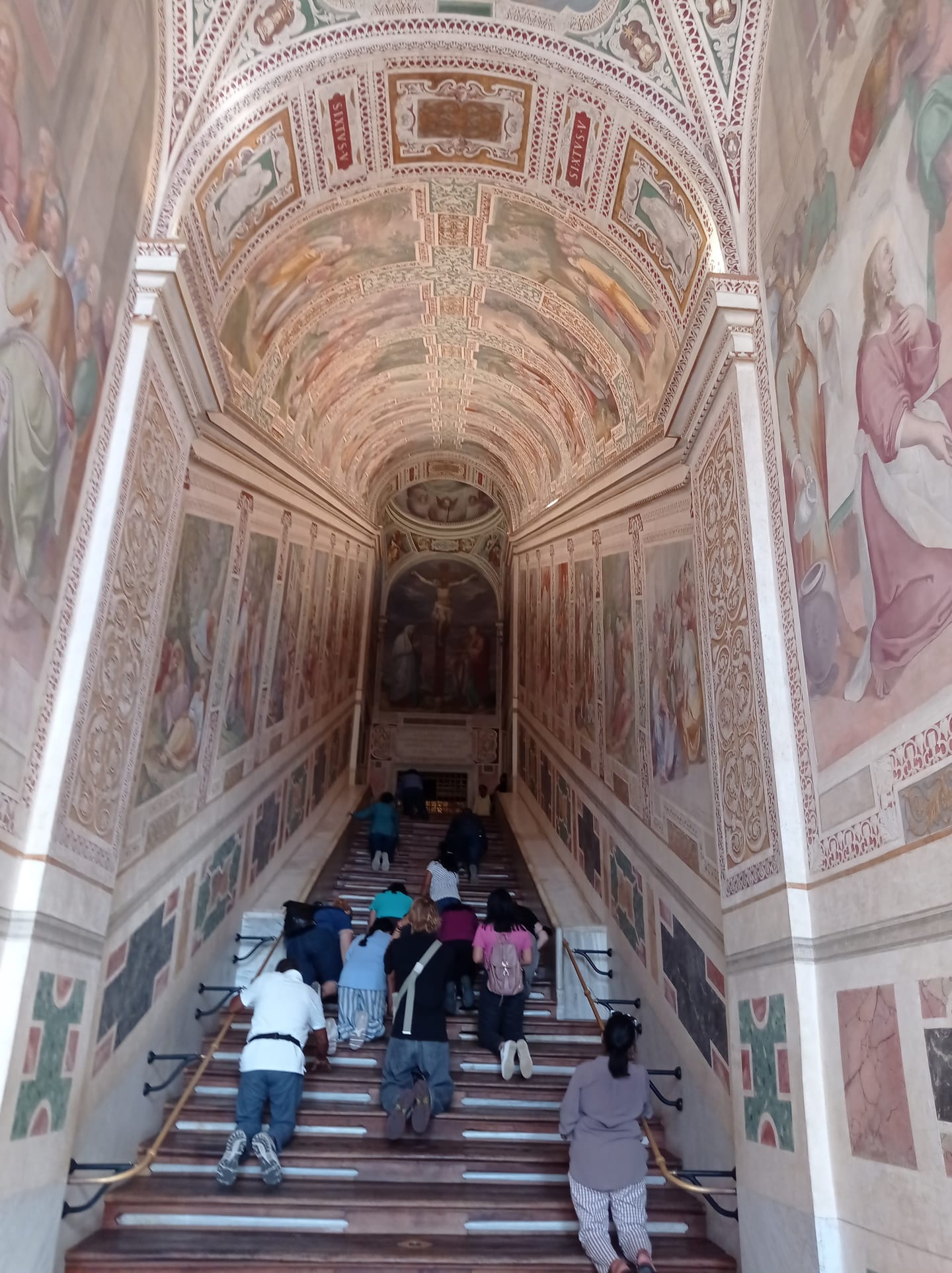 Pellegrini che salgono la Scala Santa sotto la volta affrescata